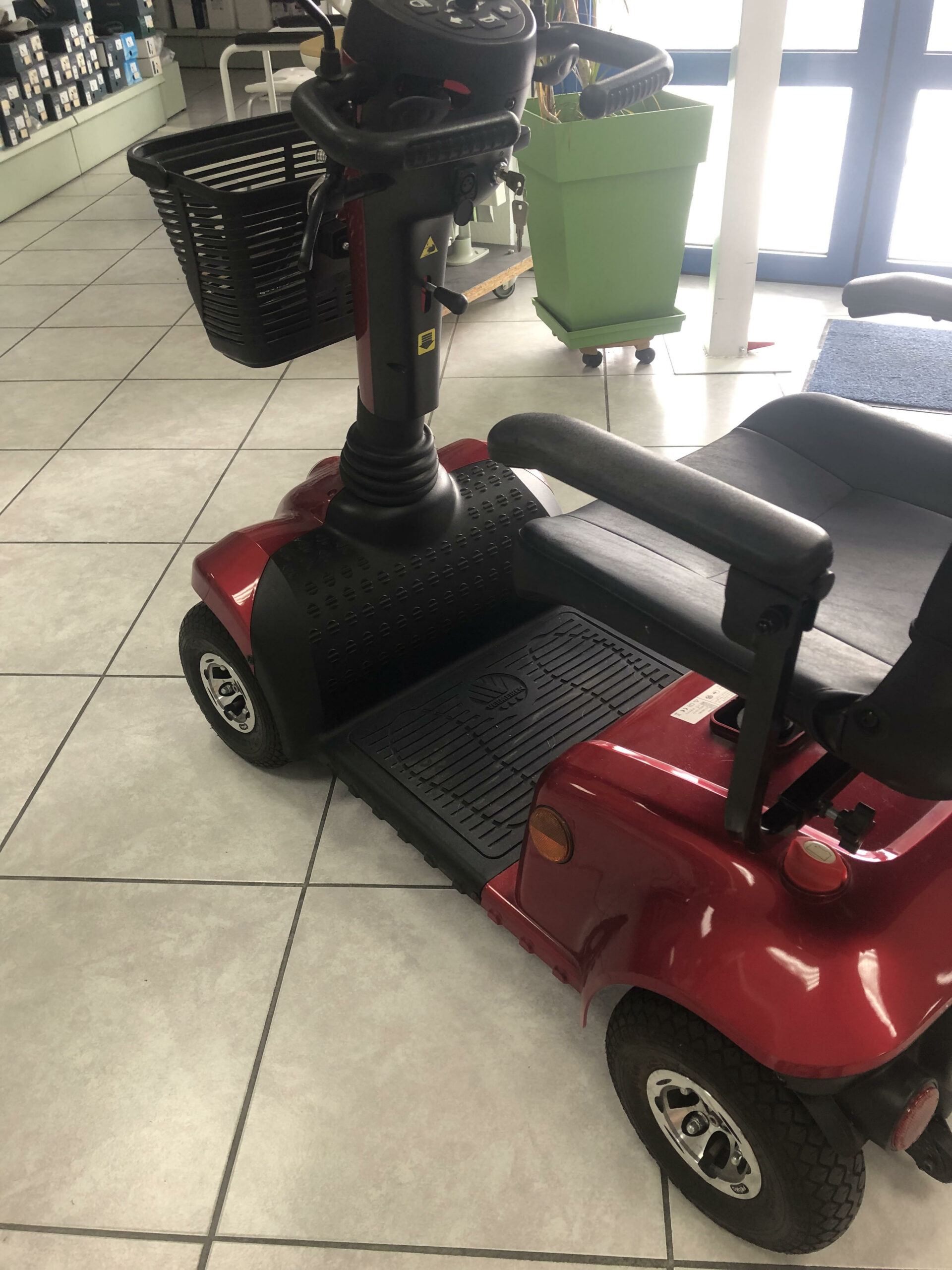Scooter de mobilité compact d’occasion rouge en vente, avec sièges et commandes noirs, disponible sur medicsante.fr dans la catégorie Matériel Occasion